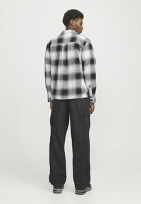Sort og hvid rutet skjorte med en afslappet pasform, tykk flannel-materiale, knapmanchetter, parret med sorte cargo-bukser med flere lommer.