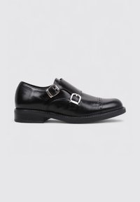 Zapato de vestir de cuero negro con doble hebilla plateada, punta redondeada, detalles cosidos y tacón bajo. Textura suave y silueta clásica.
