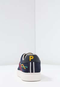 Navy suede sneaker with white sole. Features yellow 'P' logo, colorful embroidery, and two white stripes on the heel. Smooth texture.