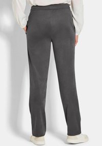 Grijze getextureerde broek met een elastische tailleband, voorzien van zijzakken en een rechte pijpontwerp, gestyled met witte sneakers.