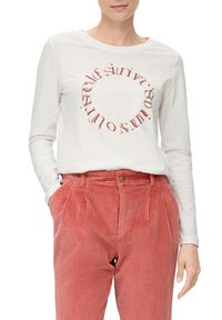 Biała koszula z długim rękawem ma okrągły czerwony nadruk z przodu. Zestawiona z różowymi spodniami z teksturowanej kordurowej tkaniny o wysokim stanie i kieszeniach.