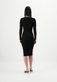 Black ribbed knit dress with long sleeves, fitted silhouette, knee-length hem, and rounded neckline; plain texture with no additional patterns.