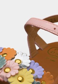 Ροζ σανδάλι με πολλαπλές πολύχρωμες διακοσμήσεις λουλουδιών με χρυσούς πυρήνες και ορατό λουράκι αστραγάλου.