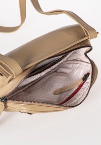 Borsa a spalla in pelle marrone con chiusura a zip, dotata di un rivestimento interno con un motivo geometrico, una tasca con zip rossa e una tracolla regolabile.