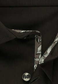 Zwarte shirtstof met een bloemenpatroon voering, voorzien van een knoopsluiting en gestikte kraagdetails. Soepele textuur en op maat gemaakt ontwerp.