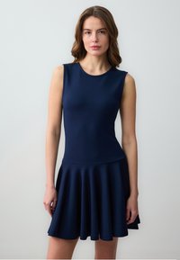 Robe sans manches navy avec un buste ajusté, une jupe �évasée, une texture lisse et un col rond. Design simple et couleur unie sur toute la surface.