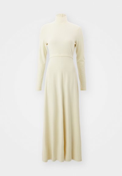 Vestido longo, de cor creme, com um decote alto, mangas longas e um corpete justo. Flui para uma saia solta, feita de um material suave.