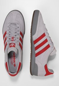 Grå mockasnakers med röda läderränder, gummisula och vadderad krage. Logotyp på tungan och insidan, platt snördesign.