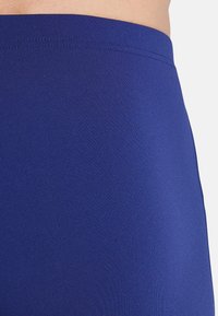 Marineblaue Sportshorts aus dehnbarem, glattem Stoff mit körpernaher Passform und flachem Bund, mit einer subtilen gerippten Struktur.