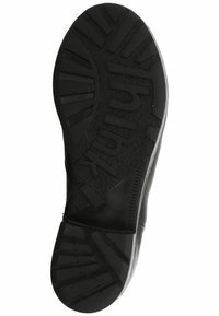 Suela de zapato negra con goma texturizada, presenta un patrón de banda de rodadura en zigzag y marca en relieve. Diseñada para ofrecer agarre y durabilidad.