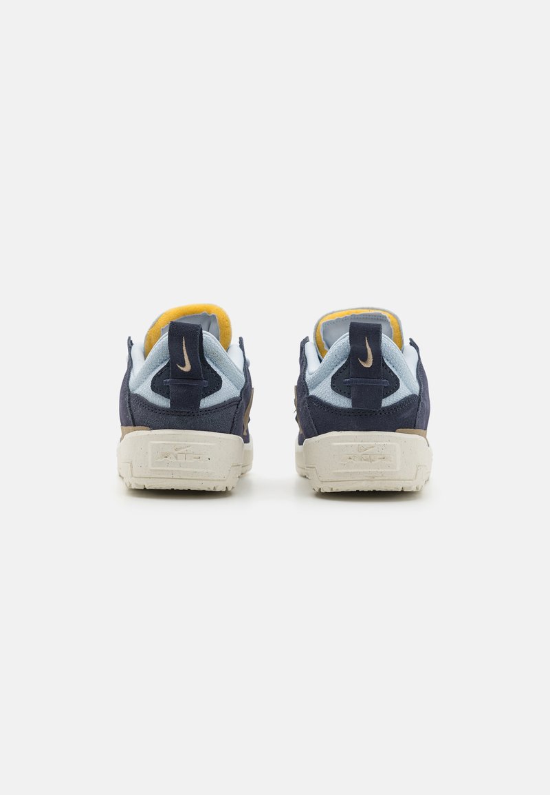 Blaue und marineblaue Stoff-Sneaker mit gelben Akzenten. Sie verfügen über ein strukturiertes Obermaterial, gestickte Details und eine weiße Sohle mit Branding.