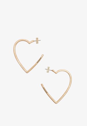 Złote kolczyki-hoop w kształcie serca z wyrytym napisem "ALLSAINTS" na sztyftach i dolnych krawędziach, prezentowane na białym tle.