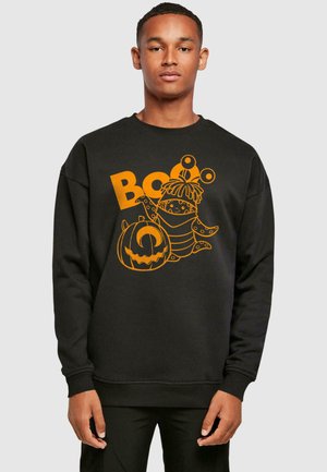 Fekete pulóver, narancssárga grafikával, amelyen egy rajzfilmfigura és egy tök látható a "Boo" felirattal. Klasszikus kerek nyakkivágás és hosszú ujjú.