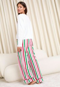 Valge pikkade varrukatega särk, millel on sooniktekstuur, koos laiale triibuliste pükstega punase, rohelise ja valge värviga. Omab vaba lõiget ja minimaalset detailide kasutamist.