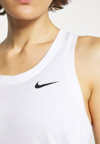 Débardeur blanc de sport avec un logo Nike noir. Le tissu semble lisse, avec une coupe ajustée et un col rond.
