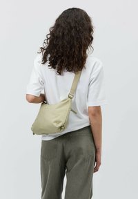 Khaki nylon torba na ramie z regulowanym paskiem, miękka w dotyku, o zaokrąglonym kształcie; wyposażona w zamek błyskawiczny i subtelny detal z logo.