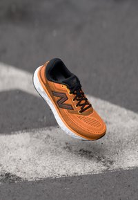 Orange løbesko med en åndbar mesh-overdel, sorte detaljer og en hvid polstret sål, som viser et tekstureret design og snøresystem.