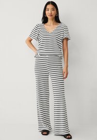 Gestreept zwart-wit twee-delig set met een V-hals, kortmouwen top en wijde broek met een relaxte pasvorm en zachte textuur.