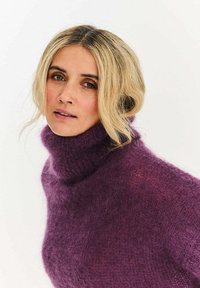 Fialový rolákový sveter z mäkkého, chlpatého materiálu s voľným strihom a rebrovaným výstrihom, ktorý zdobí bohatý, štruktúrovaný vzor.