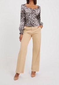 Long-sleeve, leopard-print blouse with a square neck and ruching detail, paired with high-waisted beige wide-leg pants and nude heels.