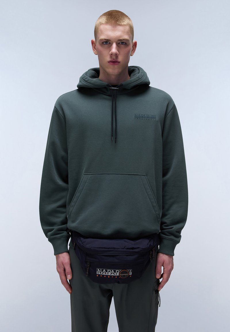 Felpa verde con tasca frontale e cappuccio regolabile, abbinata a una cintura fanny pack blu navy con un patch logo. Tessuto dal tocco morbido.