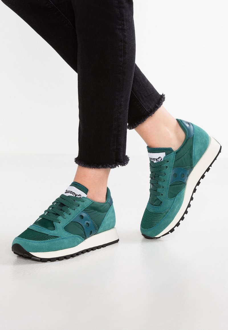 Baskets vertes en mesh et en daim avec une semelle rembourrée, dotées d'un laçage, d'un logo et d'une semelle extérieure en caoutchouc.