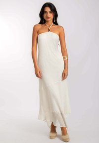 Vestido maxi blanco sin tirantes con un patrón texturizado, que presenta un corsé ajustado, un dobladillo fluido y se lleva con zapatos de esparto en tonos neutros.