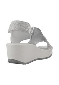 Las sandalias de cuña plateadas presentan correas plateadas texturizadas con un patrón tejido, una suela blanca de plataforma y un interior suave y liso.