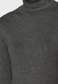 Szary sweter z golfem, charakteryzujący się prążkowaną fakturą, wykonany z miękkiej dzianiny, z dopasowanymi rękawami i wysokim kołnierzem.