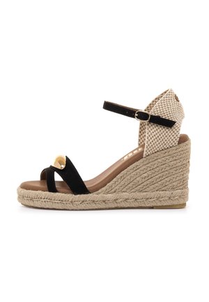 Sandalia cuña de ante negro con tacón tejido beige, con una sola tira y detalle dorado en la parte frontal. Correa ajustable en el tobillo.