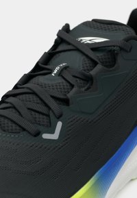 Chaussure de course noire avec une tige texturée, des lacets noirs et une semelle multicolore avec des accents bleus et verts. Marque "FWD VIA" visible.