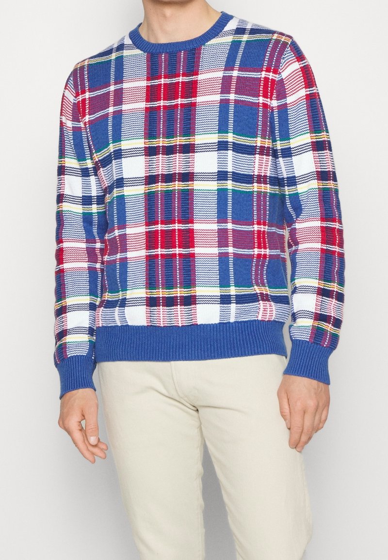 Stickad rutig tröja med inslag av blått, rött, vitt och grönt. Ribbad rundhals och muddar, med en texturerad yta.