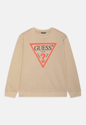 Sudadera beige con mangas largas, cuello redondo y un gran logo triangular rojo que presenta "GUESS U.S.A." y un signo de interrogación. Tejido suave.