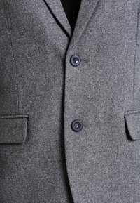 Szary wełniany blezer z wyciętym klapem, dwoma przednimi kieszeniami i dwoma przednimi guzikami o gładkim, teksturowanym wykończeniu.
