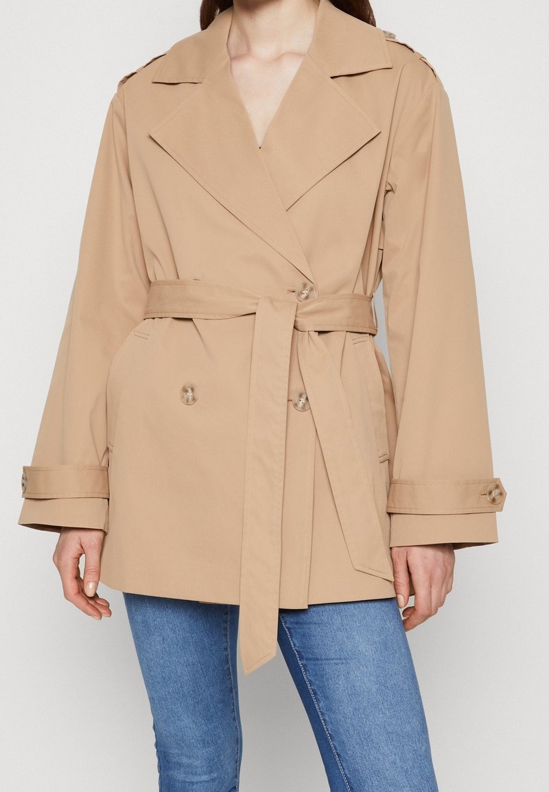 Beige trenchcoat met een dubbelzijdig ontwerp, brede revers, een ceintuur in de taille en knoopmanchetten. Glad, lichtgewicht stof.
