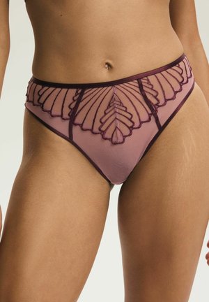 Lila Netz-Panties mit dunklen, bestickten Blattmustern, getragen an den Hüften einer Frau vor einem schlichten hellen Hintergrund.