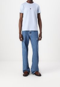 Světle modré bavlněné tričko s logem "TOMMY HILFIGER", spárované s modrými cargo džíny s bočními kapsami a pohodlným střihem. Hnědé boty.