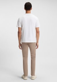 Untricou alb cu mânecă scurtă și pantaloni bej, slim fit. Tricoul are guler rotund, iar pantalonii au o croială dreaptă și buzunare la spate.