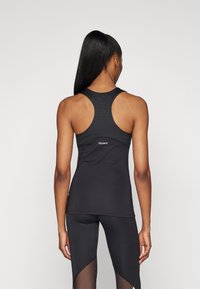 Top sportiv negru cu design racerback, având o textură netedă și detalii cu logo pe spate. Asortat cu colanți corespunzători.