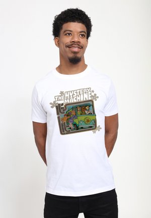 Mężczyzna w białej koszulce z postaciami z Scooby-Doo w zielonym vanie i napisem „The Mystery Machine” w stylu retro.