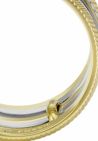 Bracelet en or et argent aux tons, présentant un design torsadé, une texture lisse et un petit accent en boucle. Logo gravé visible sur le côté intérieur.