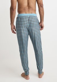 Blå rutiga pyjamasbyxor med elastisk midja och benslut. Mönstret har ljusblå rutor kantade med mörkbruna linjer.