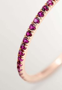 Pulsera de oro rosa que presenta una fila de gemas moradas redondas y facetadas, engastadas en un setting de garras, con un diseño de banda elegante y suave.