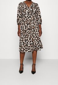 Leopardi-kuosisessa kietaisumekossa on 3/4-hihat, röyhelöhelma ja sileä pinta. Mekossa on mustia ja ruskeita laikkuja vaaleanbeigeillä taustalla. Mustat korot.