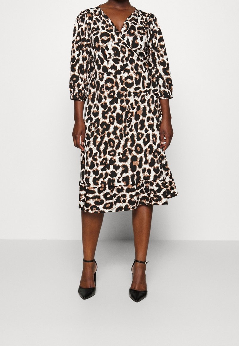 Sukienka w panterkę z rękawami 3/4, falbaną u dołu i jedwabistą teksturą. Posiada czarne i brązowe plamy na kremowym tle. Czarne szpilki.