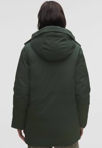 Zelená izolační bunda s kapucí, která má volný střih, hladkou texturu a jednoduchý design bez viditelných zapínání nebo vzorů.