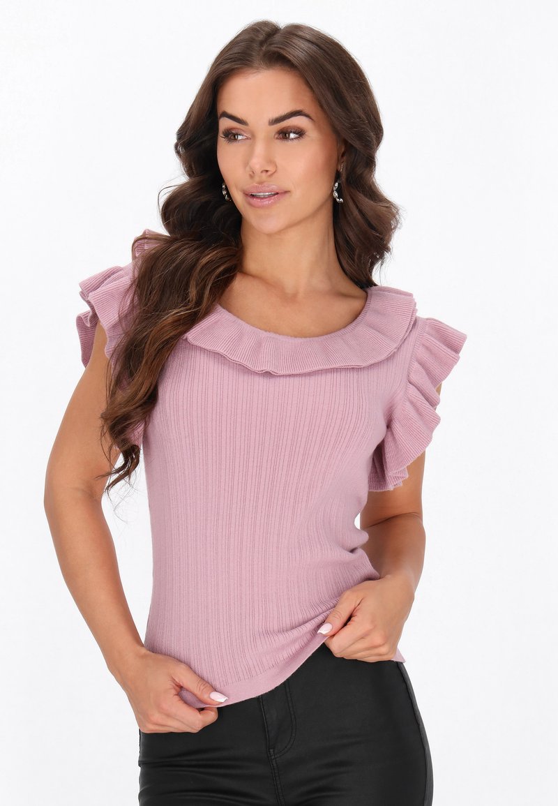 Lyserød ribbet top med korte flæseærmer og rund udskæring, parret med sorte bukser i kunstlæder.