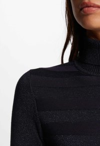 Navyblauwe coltrui met een geribbelde structuur, voorzien van glanzende horizontale strepen, een zachte textuur en een getailleerd silhouet.