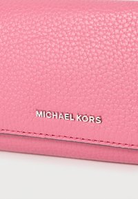 Ροζ δερμάτινο πορτοφόλι με υφή, με ασημένιο λογότυπο "MICHAEL KORS". Το σχέδιο περιλαμβάνει ραμμένες λεπτομέρειες κατά μήκος των άκρων.