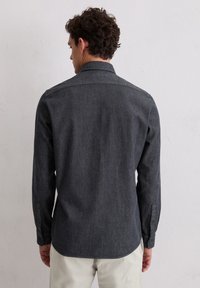 Dunkelgraues Langarmshirt mit einem umschlagbaren Kragen, glatter Webstruktur und geknöpften Manschetten. Die Rückansicht zeigt einen geraden Saum und minimale Details.